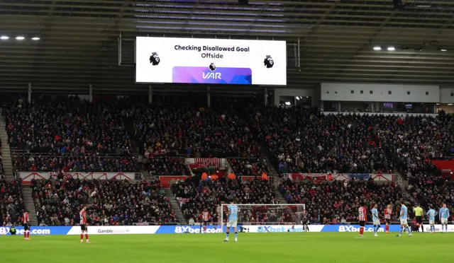 A big screen displays a VAR review message