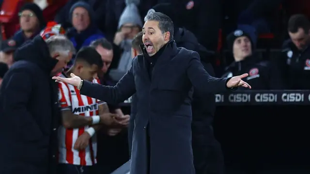 Marti Cifuentes standing on the touchline with his mouth open and his arms held out at his sides