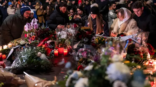 People lay down flowers outside the bar