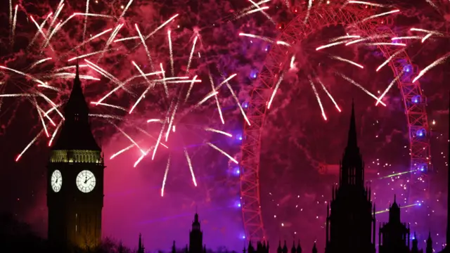 A red and purple sky can be seen behind Big Ben and the London Eye, as fireworks explode around them.