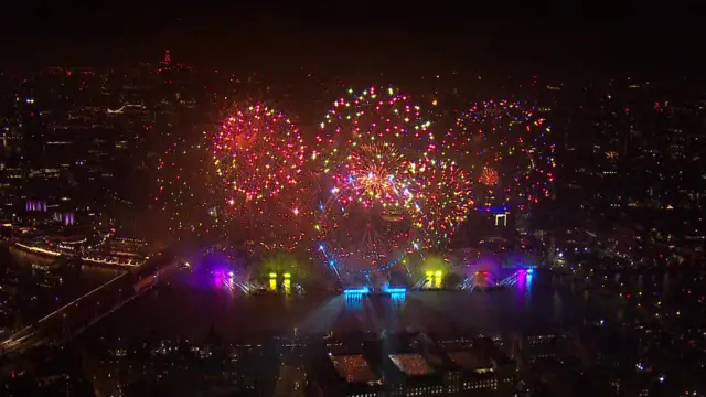 Red and yellow fireworks explode above the London Eye.