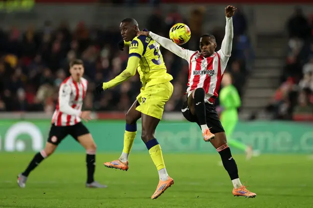 Rico Henry of Brentford battles for possession with Randal Kolo Muani