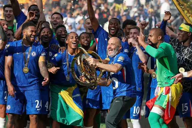 Chelsea head coach Enzo Maresca readies to raise the championship trophy over his head as players ready to celebrate after winning the FIFA Club World Cup Final between Chelsea and Paris Saint-Germain