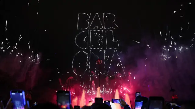 Drones form the word "Barcelona" in the night sky as fireworks light up the city during New Year celebrations.
