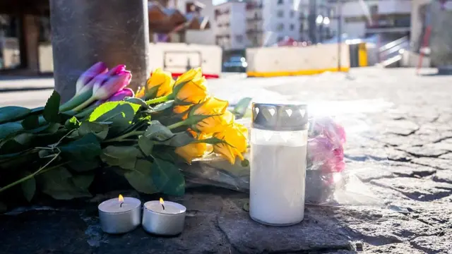 Purple tulips and yellow roses laid on the street with lit candles - in front of the screened off site outside the bar