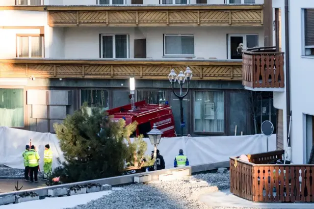 A zoomed in shot of the bar shows police in hi vis in front of white barriers and a red emergency vehicle parked outside