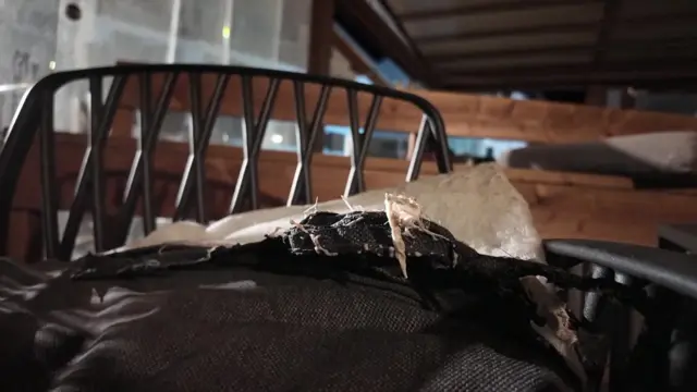 A black chair with a ripped cushion on its seat