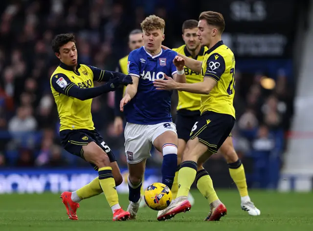 Sindre Walle Egeli of Ipswich Town battles for possession with Filip Krastev and Jack Currie of Oxford United