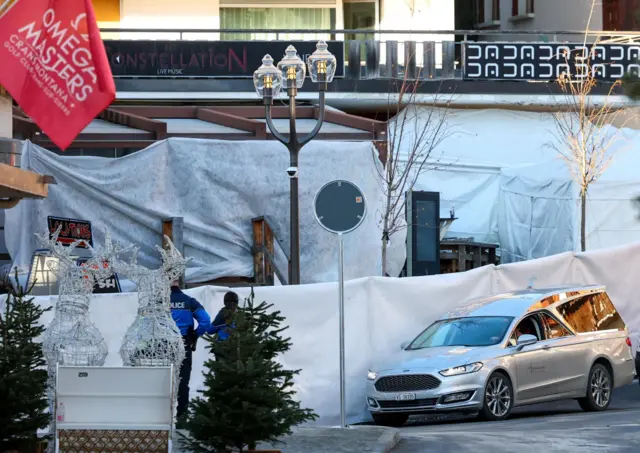 A hearse on the road outside the bar, which has been covered in white fabric