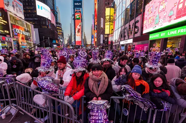 Thousands of people wearing purple hats are crammed into Times Square on New Year's Eve.