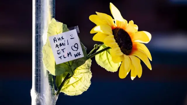 A yellow sunflower with a white square note with French writing on it