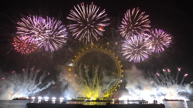 Red and yellow fireworks explode above the London Eye.