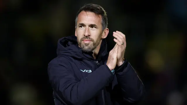 Newport County manager Christian Fuchs holds his hands up and claps at the end of a match