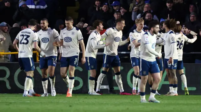 Huddersfield players stand together and celebrate in front of fans