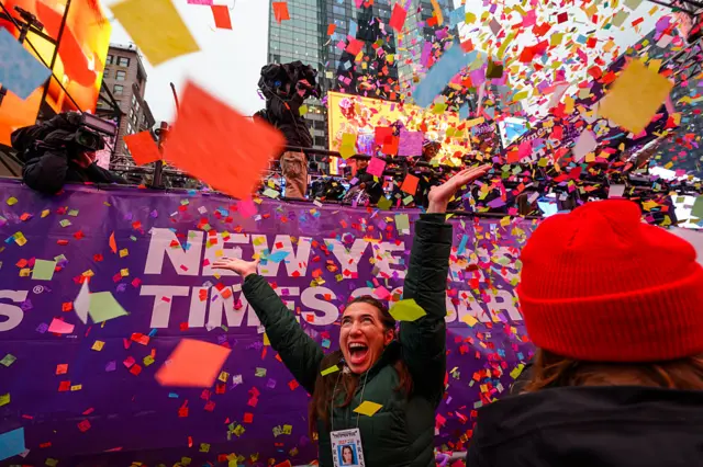 A woman cheers as confetti surrounds her head during the Times Square New Year's Eve confetti test