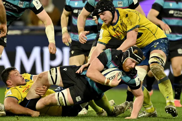 Glasgow lock Gregor Brown is tackled by Clermont's Pio Muarua and Thibault Lanen