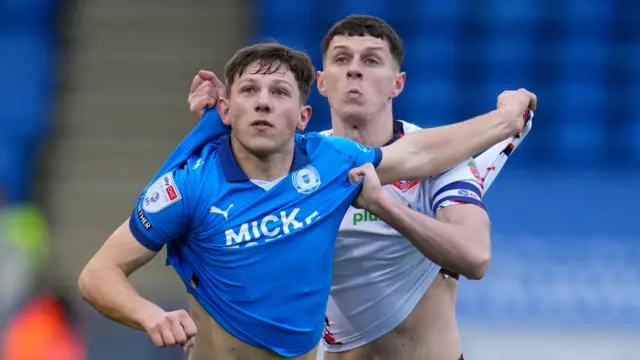 Eoin Toal of Bolton Wanderers and Harry Leonard of Peterborough United tug on each others' shirts