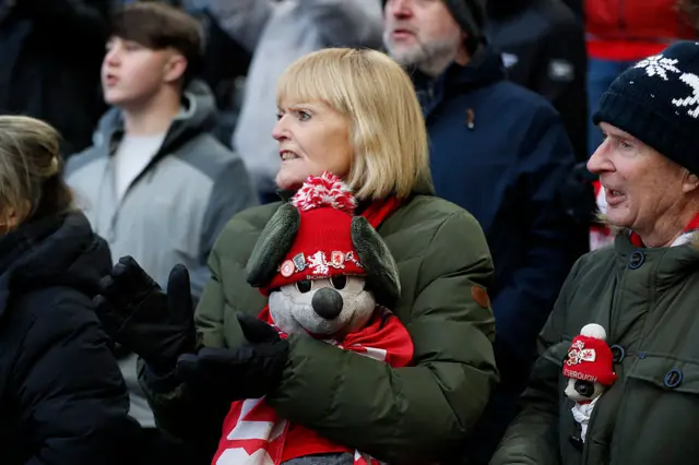 A Middlesbrough fan holds a cuddly mascot wearing a hat with Middlesbrough badges