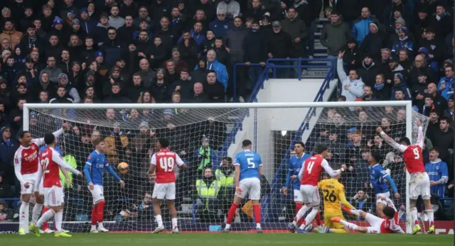 Porstmouth and Arsenal players react to the ball in the net