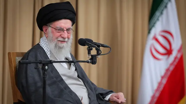 Khamenei sits in a chair with a microphone in front of him