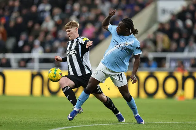 : Lewis Hall of Newcastle United is challenged by Jeremy Doku of Manchester City
