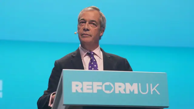 A politician stands on a podium. It is baby blue.