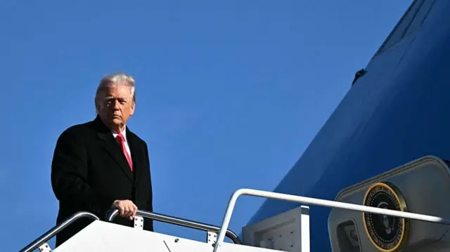 Donald Trump in a dark suit boarding Air Force One.