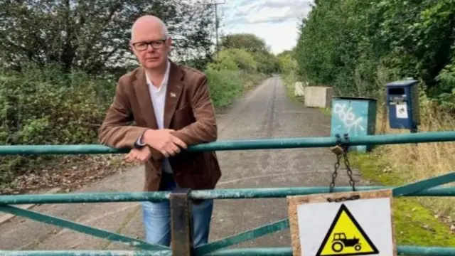 Stuart Jeffrey leans against a fence in the countryside