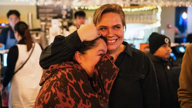 People react as they watch a press conference of Greenland's Foreign Minister Vivian Motzfeldt and Denmark's Foreign Minister Lars Loekke Rasmussen on TV