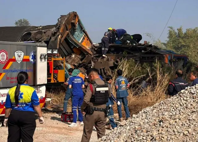 Rescuers working on the wreckage of a passenger train after a construction crane collapsed onto it in Sikhio district