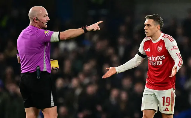 Referee Simon Hooper shows a yellow card to Arsenal's Belgian midfielder #19 Leandro Trossard