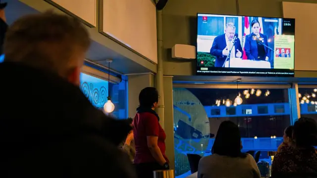 People watch a press conference of Greenland's Foreign Minister Vivian Motzfeldt and Denmark's Foreign Minister Lars Loekke Rasmussen on TV in a restaurant