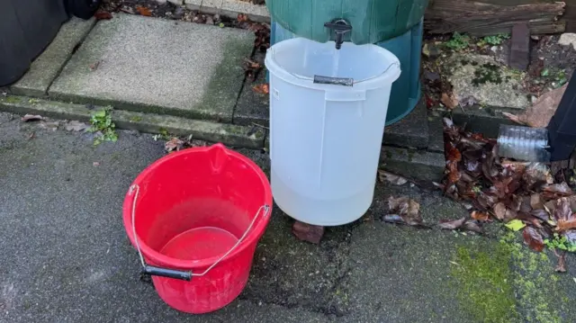 A bucket is filled up with water from a butt.