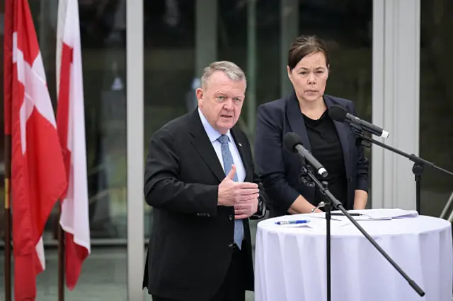 Danish Foreign Minister Lars Løkke Rasmussen and Greenland's Foreign Minister Vivian Motzfeldt speaking to a press conference at a table with a white table cloth and next to the Danish and Greenlandic flags