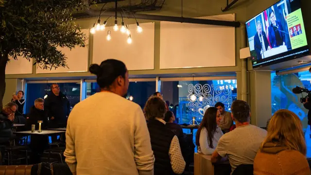 People watch a press conference of Greenland's Foreign Minister Vivian Motzfeldt and Denmark's Foreign Minister Lars Loekke Rasmussen on TV in a restaurant