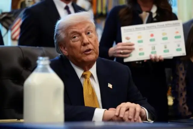 Donald Trump sits at his desk in the Oval Office beside a large bottle of milk