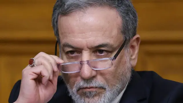 Iran's Foreign Minister Abbas Araqchi adjusts his glasses