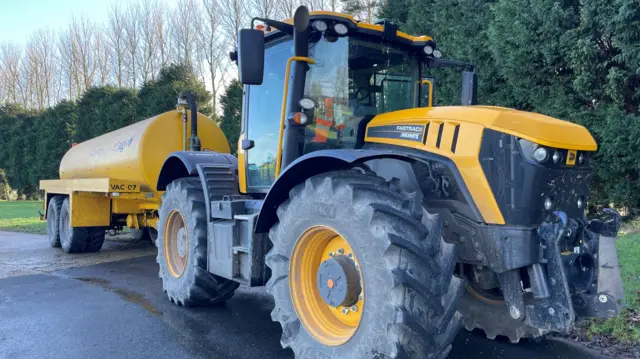 A yellow tractor pulling a yellow water tank.
