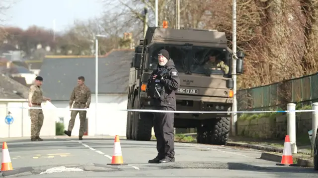 A member of the police stands in front of a military vehicle in the area