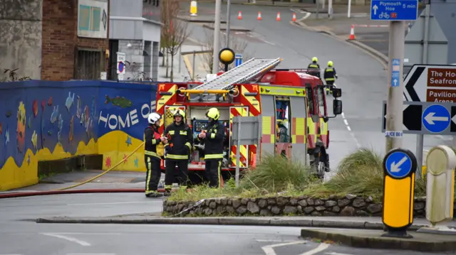 A fire crew stood around a fire engine on a road in Plymouth