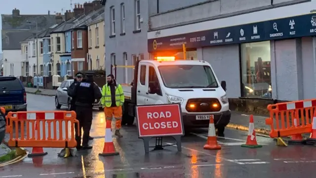 A view of a road closed sign and police officers