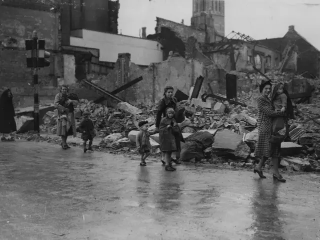 A black and white image showing rubble and people on the street of Plymouth during the blitz attacks on the city in the second world war.