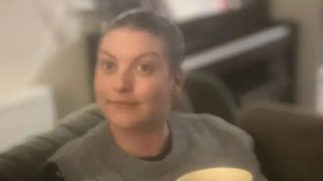 Rachel Nicholls holding a yellow mug, She is looking directly at the camera.