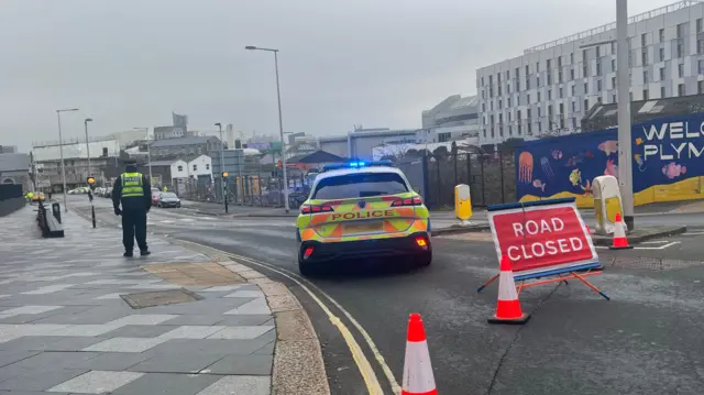Police officer, car and road closed sign in Plymouth