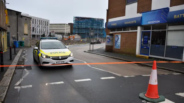 Police car behind tape and cones as part of a cordon in the Millbay area of Plymouth