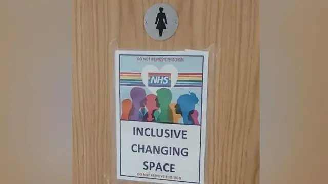 A poster on a door with the words "inclusive changing space" in large letters