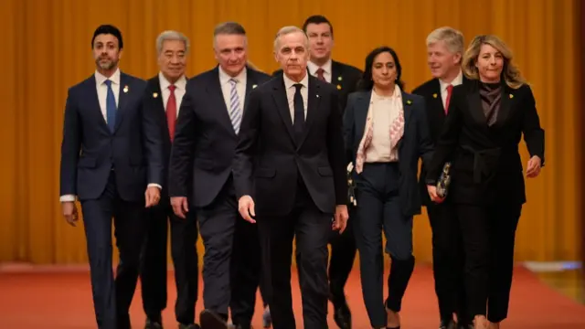 Carney walking on a red carpet with his delegation