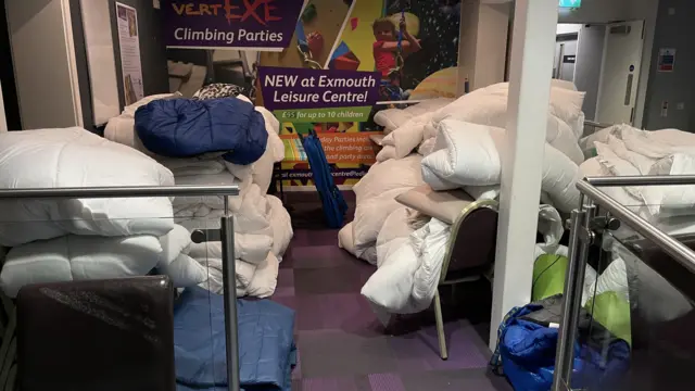Duvets, bedding and sleeping bags piled up on chairs