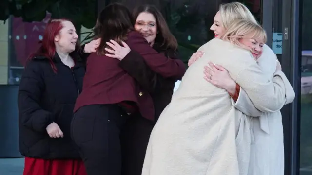 A group of nurses hug as they leave a press conference