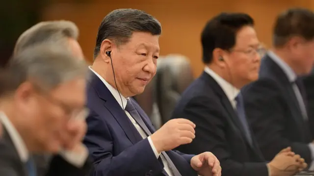 Xi Jinping listening to something with a earpiece
